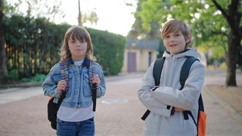 Two school kids with backpacks standing outdoors as school boys chat together. Stock Footage 338139931