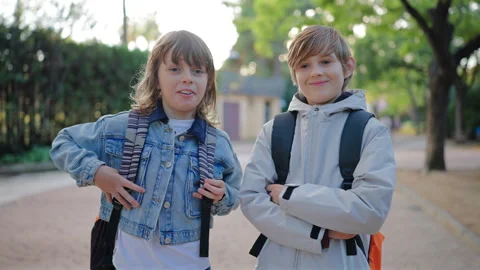 Two school kids with backpacks standing in park talking and laughing together. Stock Footage 338140122