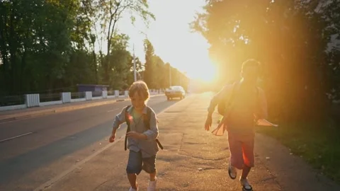Two schoolboys with a backpacks running on street at sunset time. Back to school Vídeos de archivo 157700339