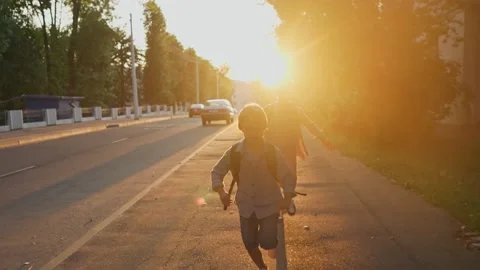 Two schoolboys with a backpacks running on street at sunset time. Back to school Video stock 157822732