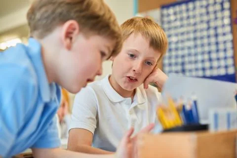 Two schoolboys problem solving in classroom at primary school Stock Photos