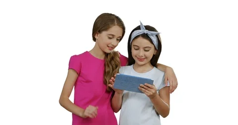 Two schoolgirls friends using tablet device while standing together on the white Stock Footage 104309335