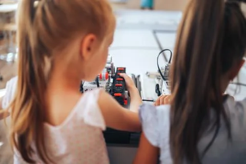 Two schoolgirls study in a robotics class, assemble a robot constructor Stock Photos