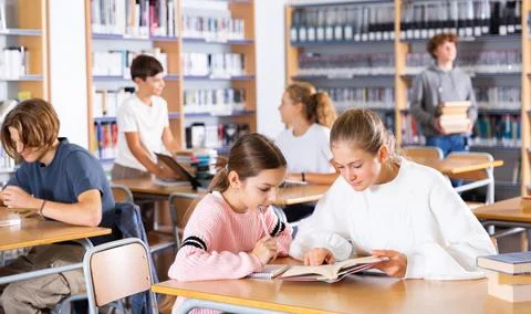 Two schoolgirls take notes in a exercise book of the necessary material from the Stock Photos