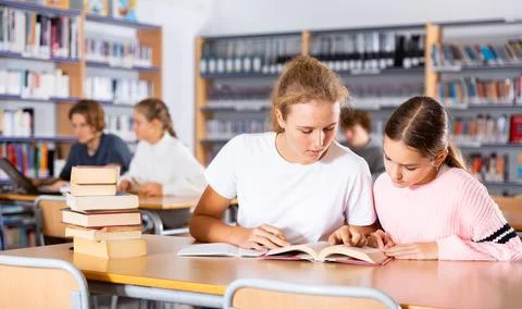 Two schoolgirls take notes in a exercise book of the necessary material from the Stock Photos