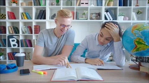 Two schoolmates preparing for exam in library. Teen girl and boy readin Stock Photos