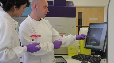 Two Scientist looking at DNA on gel image analyser Stock Footage 5091307