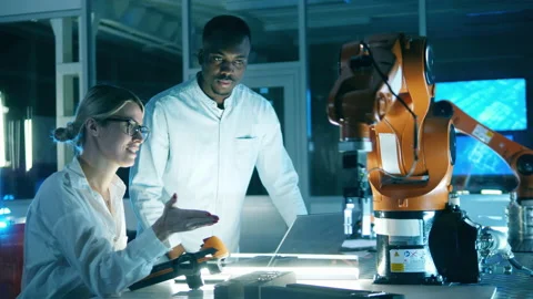Two scientists are watching a functioning robotic arm. Team of engineers working Video stock 148317986