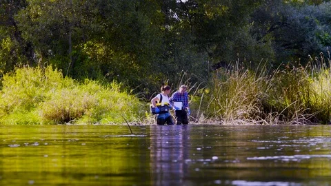 Two scientists ecologists in high rubber boots walking in the water of the Video stock 95307023