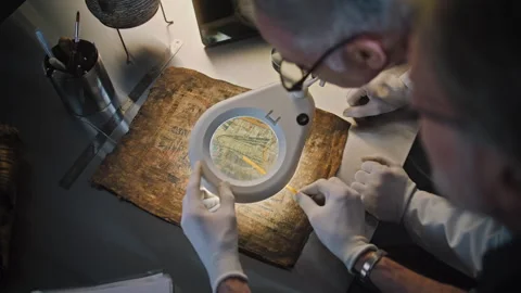 Two scientists examine ancient Egyptian papyrus together in archaeological lab Stock Footage 282160278