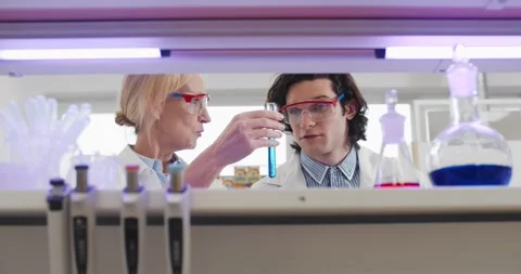 Two scientists holding test tube with blue liquid sample and sharing high five Stock Footage 152157437
