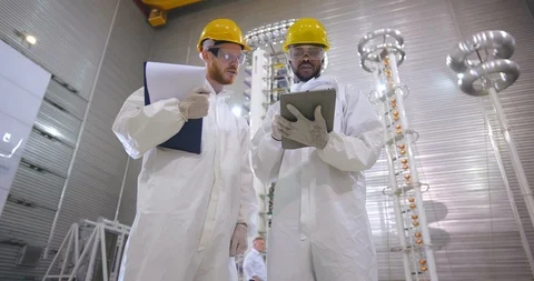 Two scientists in protective clothes and hardhats discuss results of project Stock Footage 121099719