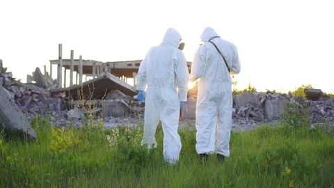Two scientists in protective suits and masks and a Radiation supervisor , walk Stock Footage 110347475