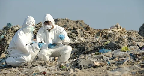Two scientists in protective suits makes inspection in landfill. Video stock 129848397