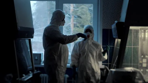 Two scientists in protective suits stand and discuss in a laboratory. Stock Footage 314342666