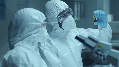 Two Scientists in Protective Uniform Discussing Blood Sample in Laboratory Stock Footage 275490658