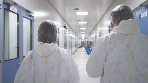 Two scientists talking and wearing protective suit walking through manufacture Stock Footage 120419658