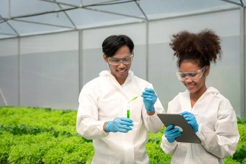 Two scientists working on tablet and holding test tube to researching about.. Stock Photos