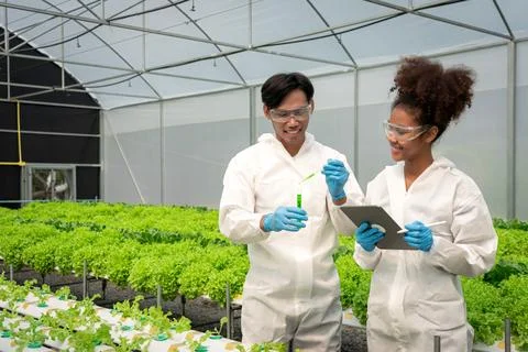 Two scientists working on tablet and holding test tube to researching about.. Stock Photos