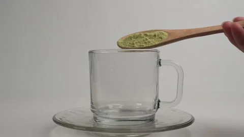 Two scoops of green tea or matcha powder into a glass cup Stock Footage 278017837