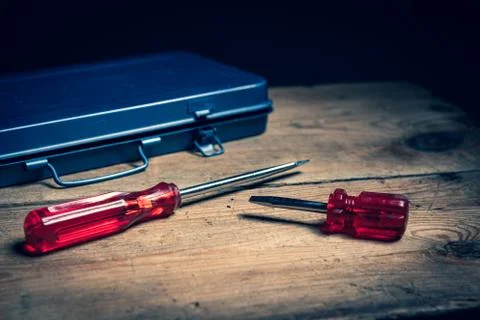 Two screw drivers and a tool box on a wooden surface Stock Photos