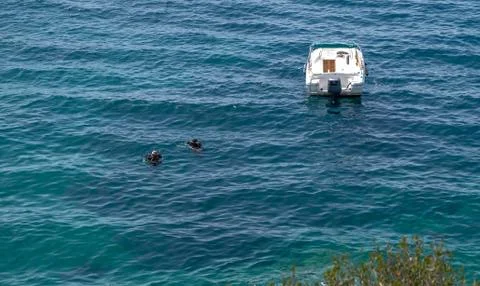 Two scuba divers dive on the surface of the sea near their boats Stock Photos