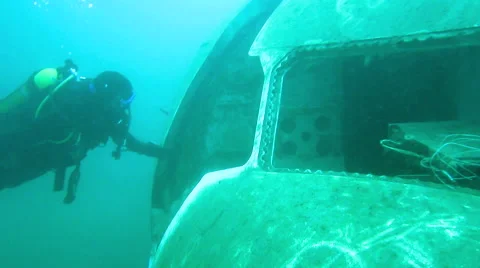 Two Scuba divers at plane wreck - one in the cockpit salutes like a pilot Stock Footage 48585995