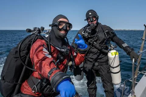Two scuba divers ready to enter the water. Side mount tank. Ocean and blue sky Stock Photos