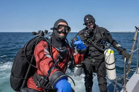 Two scuba divers ready to enter the water. Side mount tank. Ocean and blue sky Stock Photos