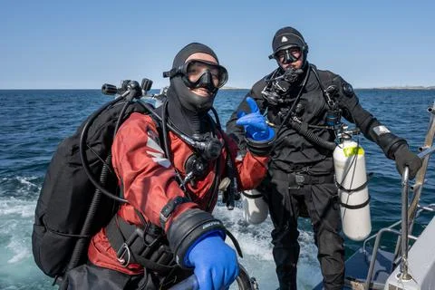 Two scuba divers ready to enter the water. Side mount tank. Ocean and blue sky Stock Photos