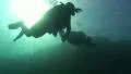 Two scuba divers swim past camera silhoutted by the Sun HD Footage
