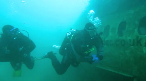 Two Scuba Divers swim up to a plane wreck Stock Footage 48587735