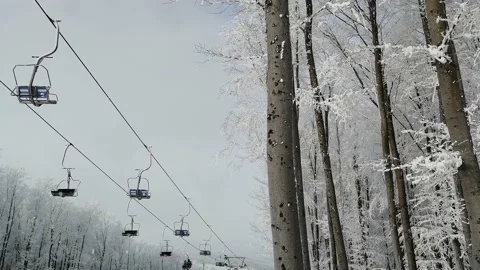 Two-seat cable car on a ski track in the winter snowy forest. Stock Footage 143432557