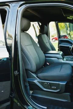 Two seats are visible in the front of a black truck parked in a driveway. The Stock Photos