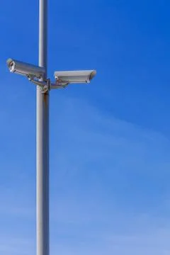 Two security cameras against the blue sky are monitoring. Foto stock