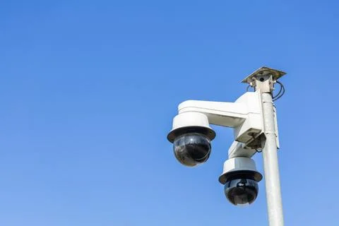 Two security cameras are mounted on a pole, watching over the area under a cl Stock Photos
