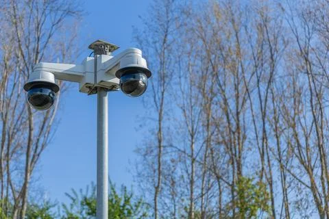Two security cameras are mounted on a pole, watching over the area under a cl Stock Photos