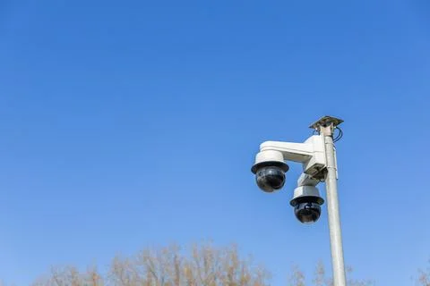 Two security cameras are mounted on a pole, watching over the area under a cl Stock Photos
