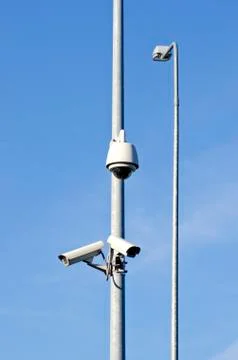 Two security cameras on electric post and lamp Stock Photos