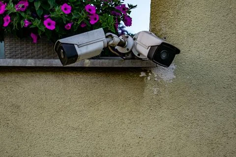 Two Security Cameras Mounted on Exterior Wall of Building monitoring state Stock Photos