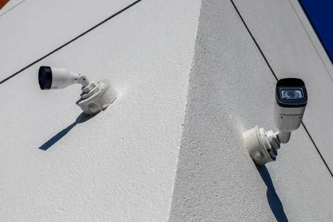 Two security cameras mounted on a sharp corner of a white building, capturi.. Foto stock