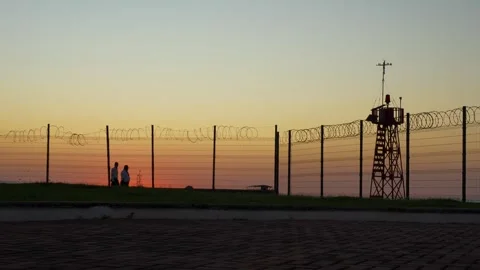 Two security guards walking the barb wire fence Stock Footage 293921978