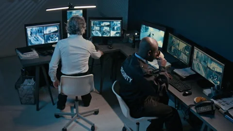 Two Security Officers Watching Multiple Screens Showing Cctv Feed at Night Stock Footage 330607643