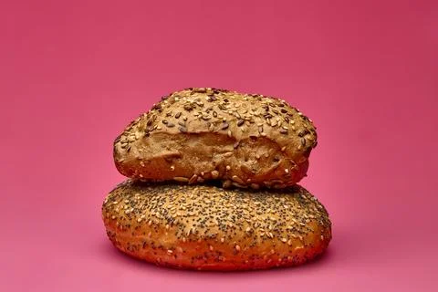 Two seeded bread rolls stacked on pink background Stock-Fotos