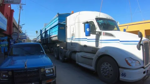 Two Semi trucks with full loads slowly driving through  the crowded 스톡 동영상 169928247