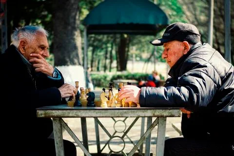 Two senior elderly man playing chess in a public park Stock Photos