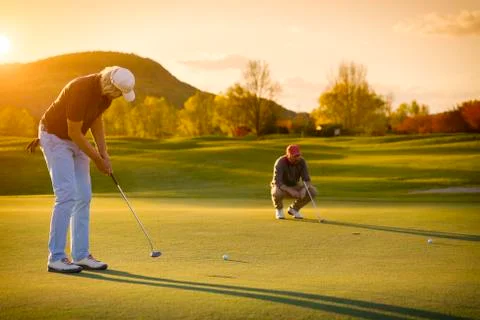 Two senior golf player at sunset. Stock Photos