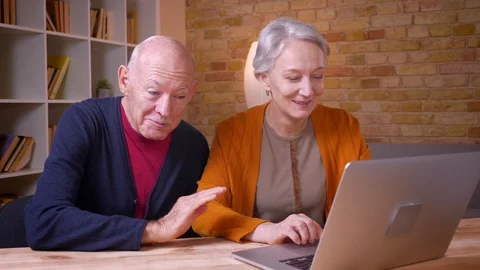 Two senior gray-haired caucasian colleagues talking in videochat on laptop being Video stock 108856975