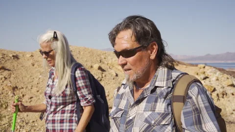 Two senior is hiking at rocks area during sunshine weather. Stock Footage 252785366