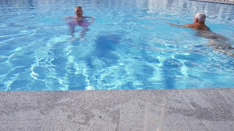 Two senior men enjoying a refreshing swim in a pool Stock Footage 203953262
